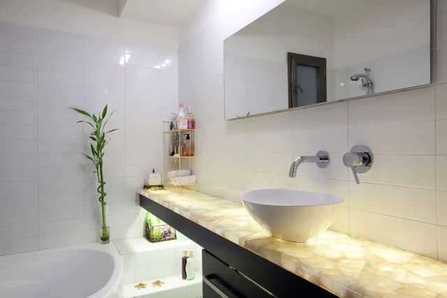 Bathroom with an illuminated stone vanity, vessel basin and freestanding bath