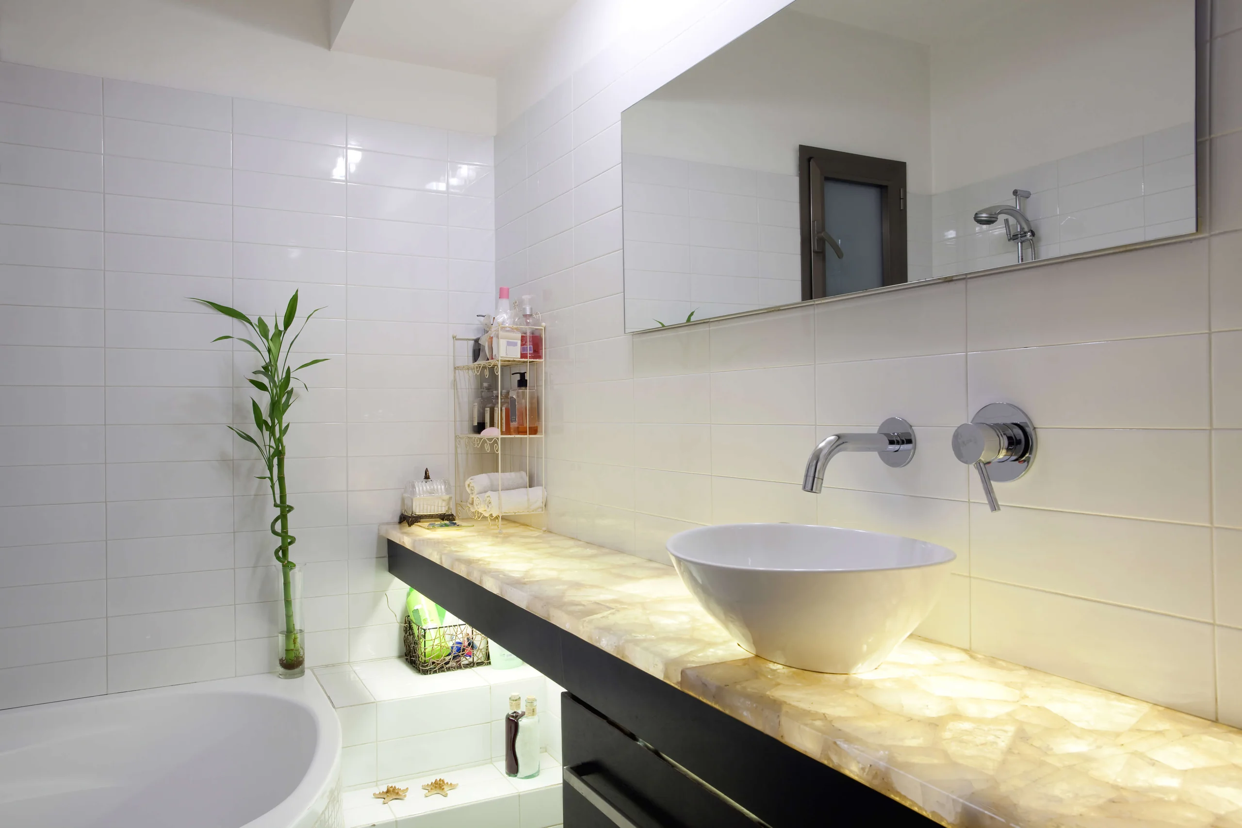 Bathroom with a glowing translucent stone vanity, a round vessel sink and a freestanding bathtub