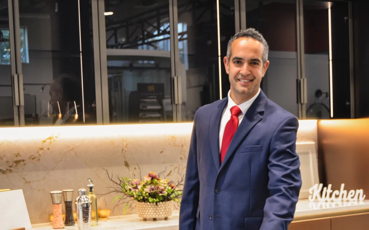 Dhiego Lopes standing beside a veined stone countertop and illuminated backsplash