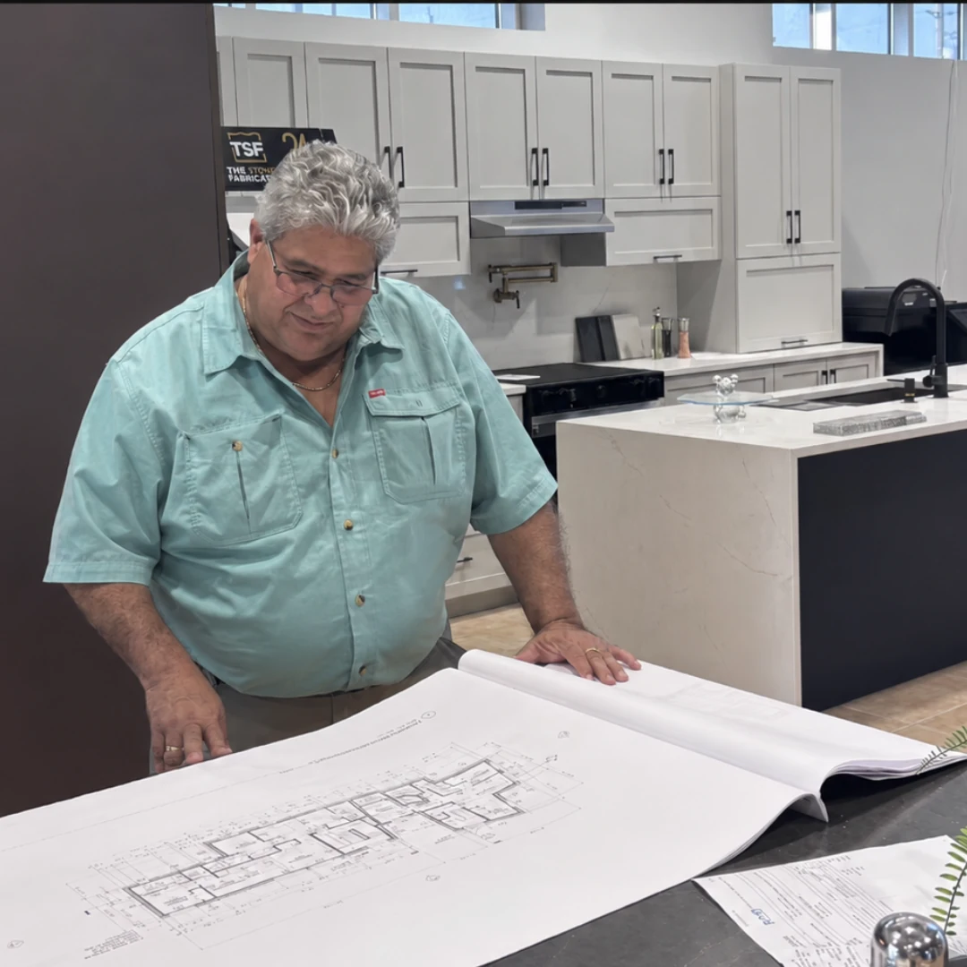 Roldan Guerrero reviewing architectural drawings at a stone countertop